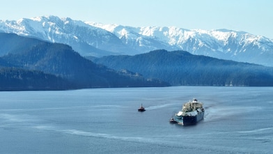 LNG tanker in a body of water at the base of mountains.