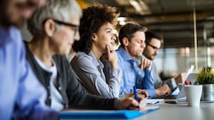 Professionals with laptops and notepads sitting in a row