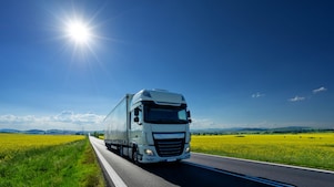 lorry driving on a road next to rapeseed field