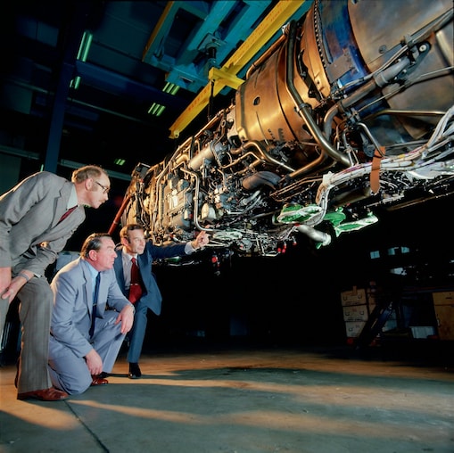 Three men are checking jet engine