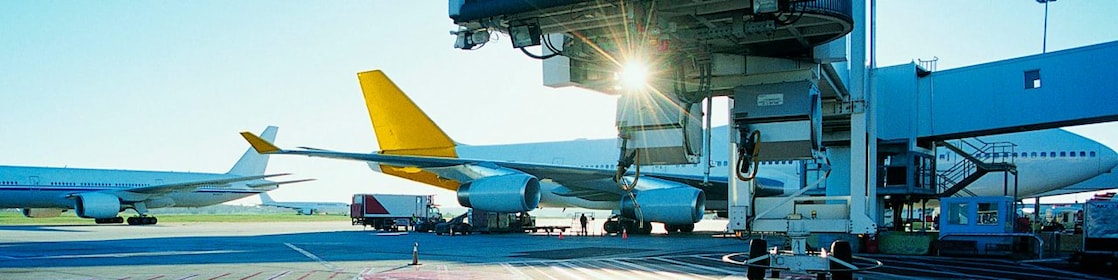 View of an airport runway in the early morning with the sun rising over two aeroplanes