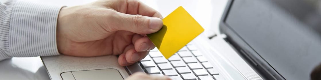 Person scrolling laptop with shell card in hand