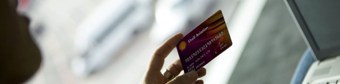 Person holding shell carnet card in front of laptop