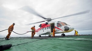 3 individuals working together to fuel a helicopter