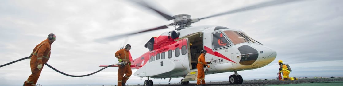 3 individuals working together to fuel a helicopter