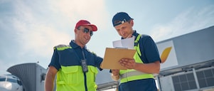 Two men working together and checking reports in an airport