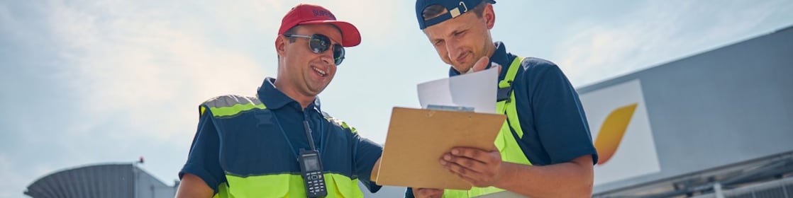 Two men working together and checking reports in an airport