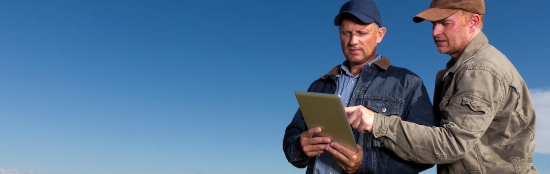 Two farmers reviewing information on tablet