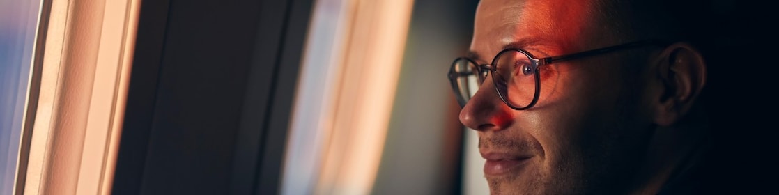 Bespectacled passenger looks out of  plane window