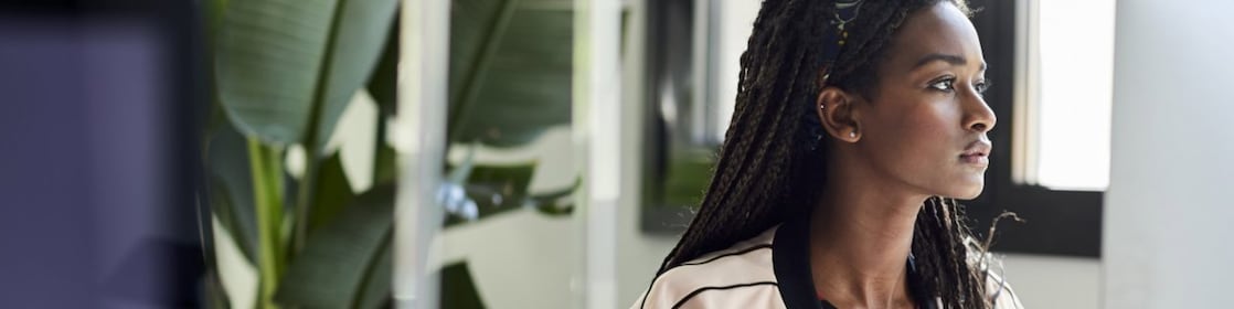 Confident businesswoman using computer at desk by window in creative office