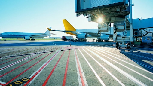 View of an airport runway in the early morning with the sun rising over two aeroplanes