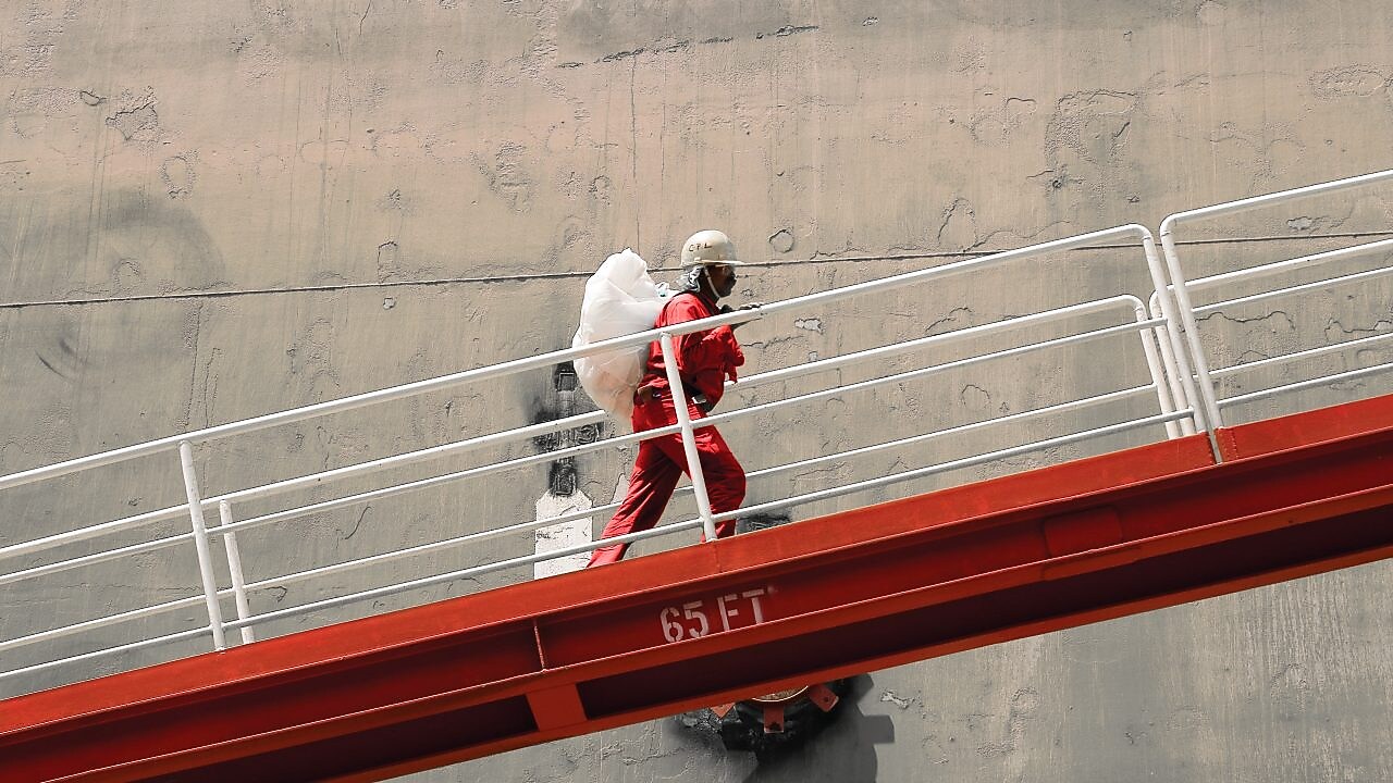 Employee climbs ramp to LNG ship.