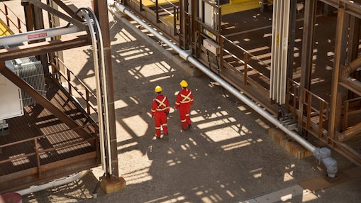 Field engineers in red jumpsuits and yellow hard hats walking through the Quest CCS facility.