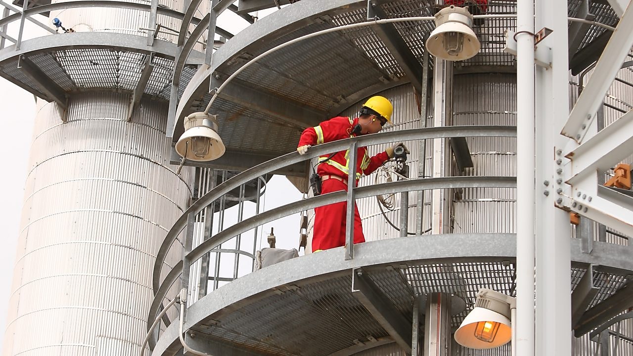 A Shell employee looks over refinery equipment from an elevated position.