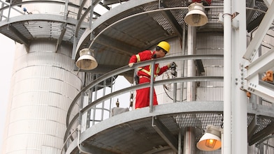 A Shell employee looks over refinery equipment from an elevated position.