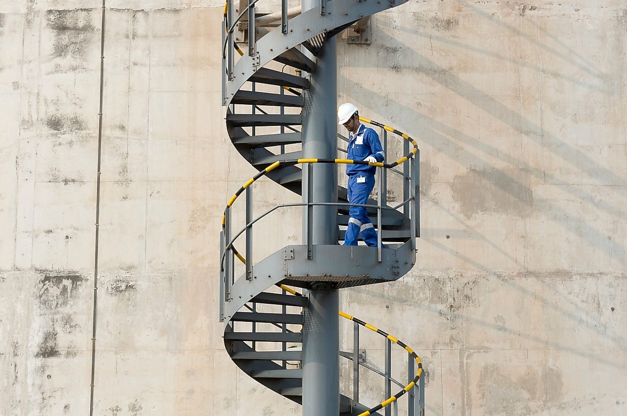 Worker descending the stairs of a LNG tank at hydrocracking facility