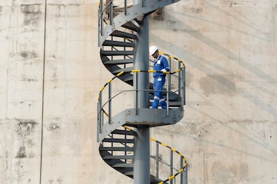 Worker descending the stairs of a LNG tank at hydrocracking facility