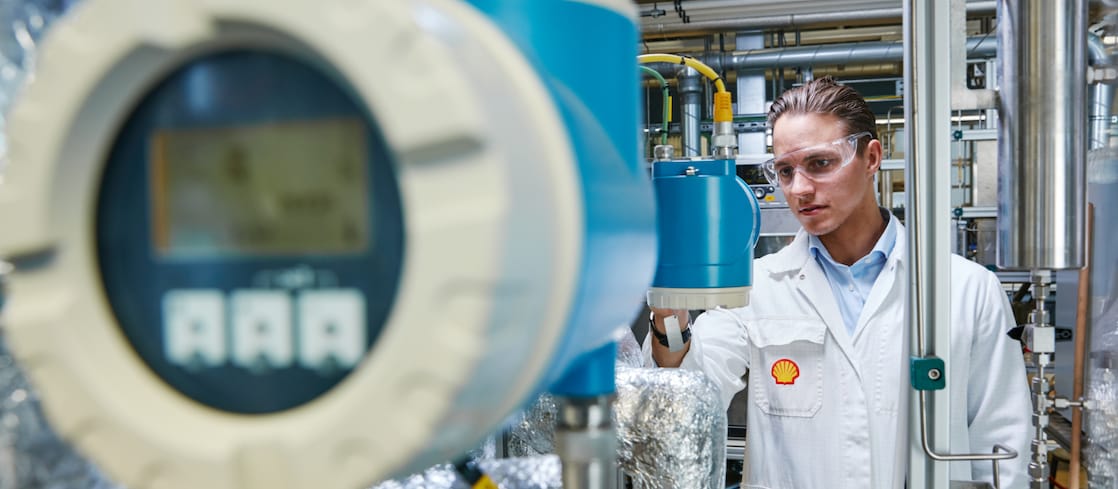 Shell engineer in a white labcoat reviews reactor internals