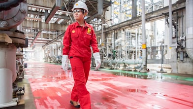 A female engineer walks through a refinery plant