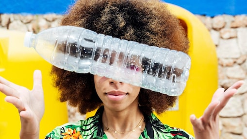 A woman is tossing a plastic bottle between her hands.