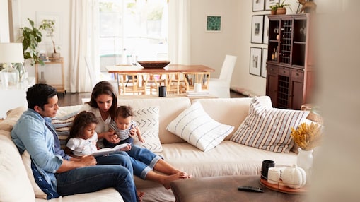 A family is reading a book together on a couch.