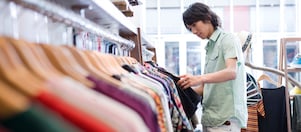 The image shows a man shopping for clothes that are made of polyester fibres.