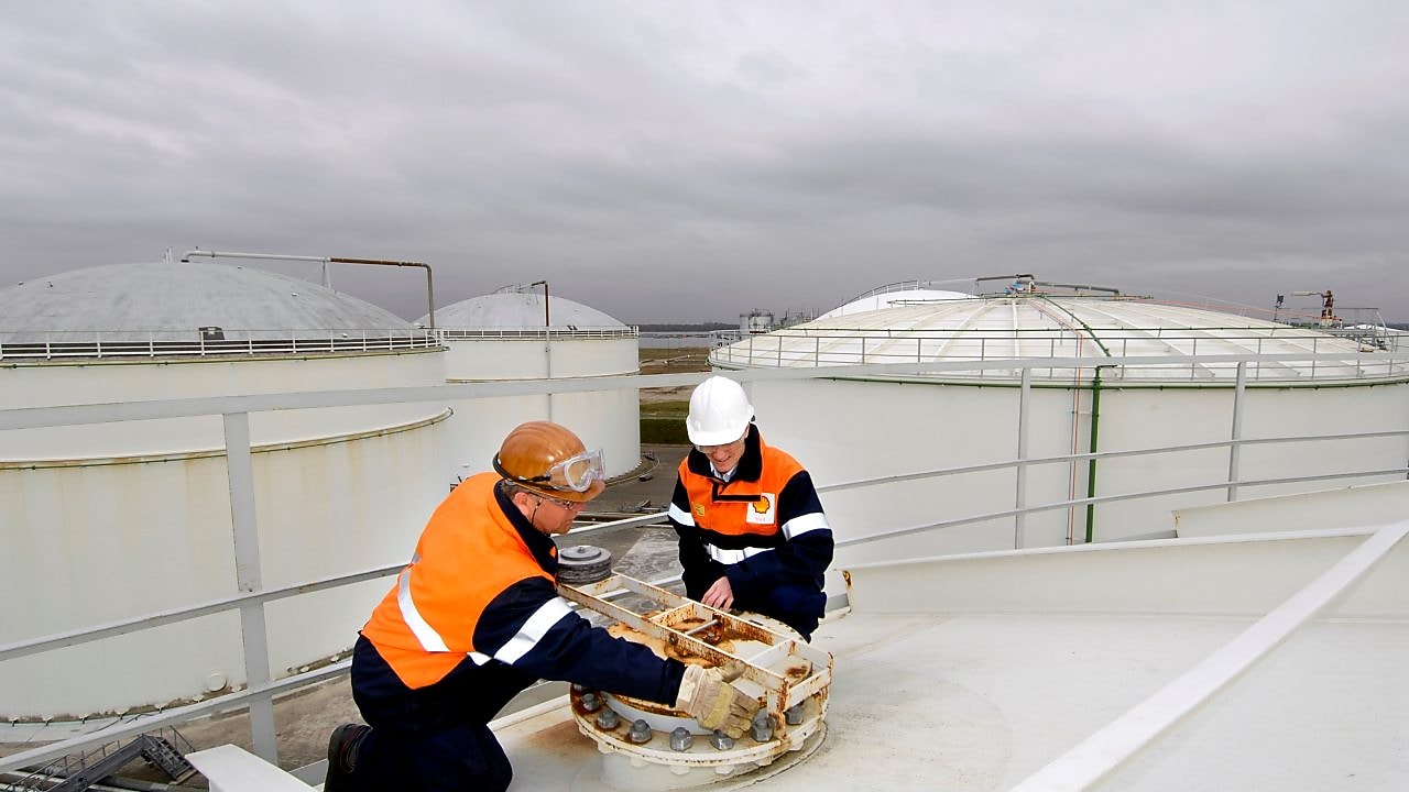 Two workman fixing a lid on a tank at a chemical plant