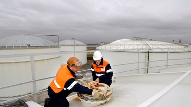Two workman fixing a lid on a tank at a chemical plant