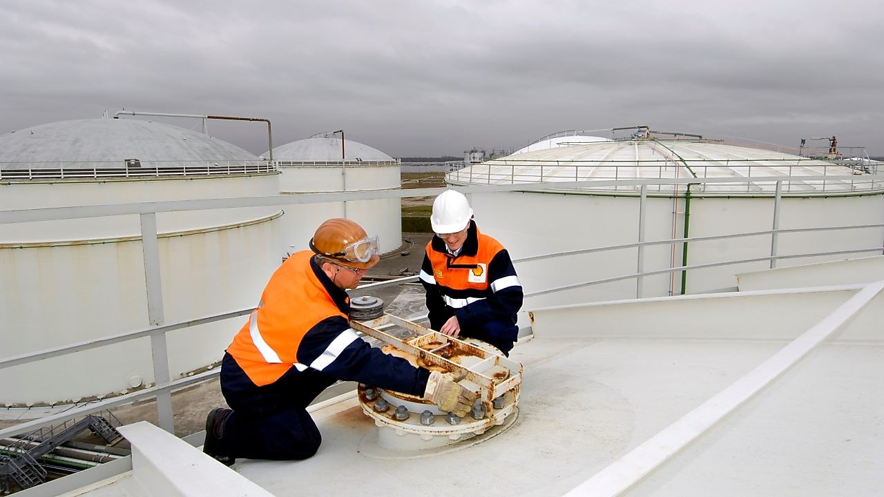 Two workman fixing a lid on a tank at a chemical plant