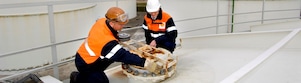 Two workman fixing a lid on a tank at a chemical plant