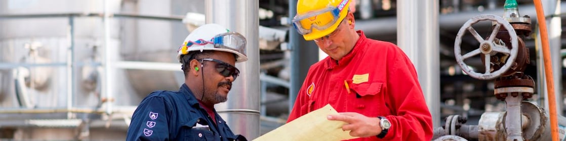 Two workman at a Shell chemical plant discuss plans