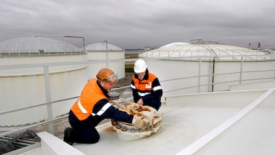 Two workman fixing a lid on a tank at a chemical plant