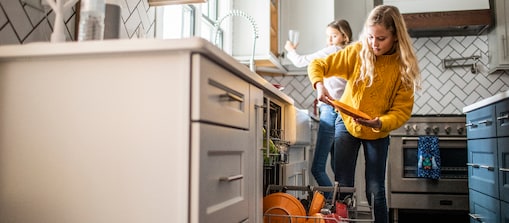 A kid is placing the plates into the dishwasher.