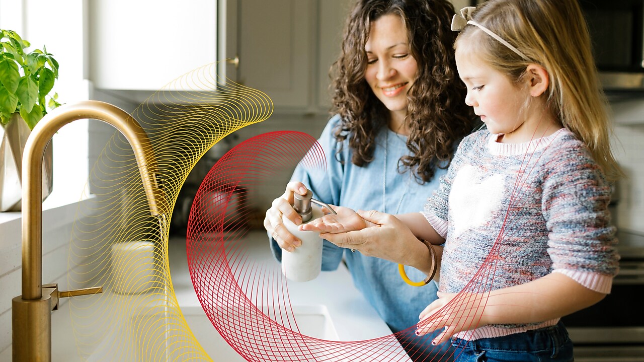 Mother and daughter wash their hands at kitchen sink