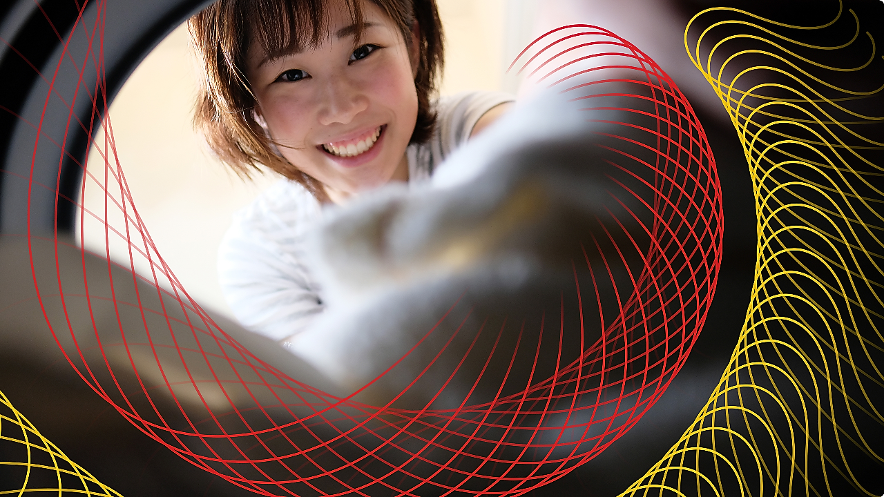 Smiling person loading laundry into a washing machine