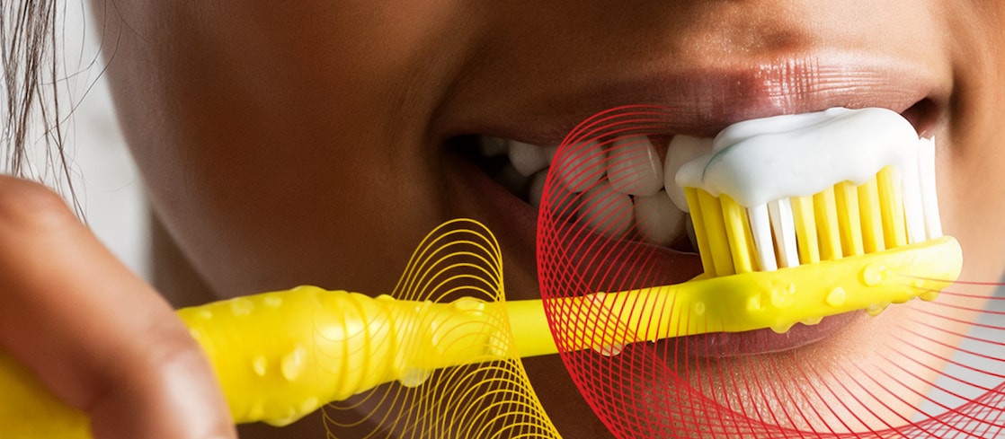 Person brushing teeth with yellow toothbrush