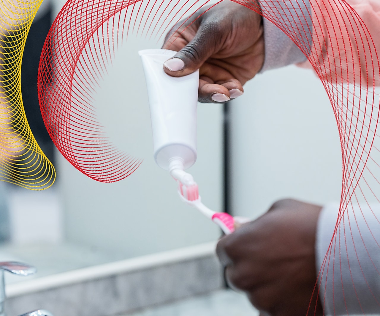 Person putting toothpaste on pink and white toothbrush
