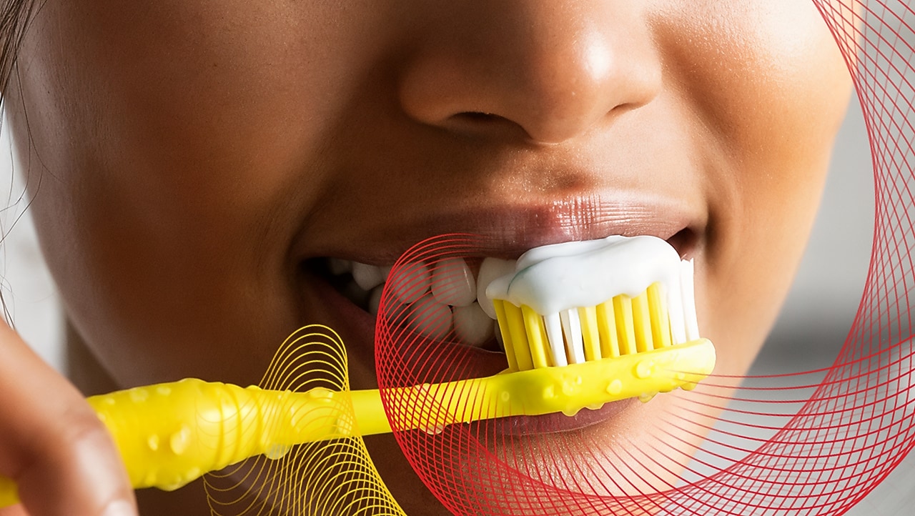 Person brushing teeth with yellow toothbrush