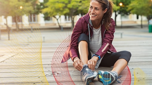 Woman lacing up running shoes and sitting on the ground