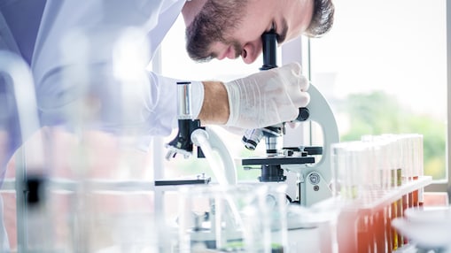 man looking through microscope in lab