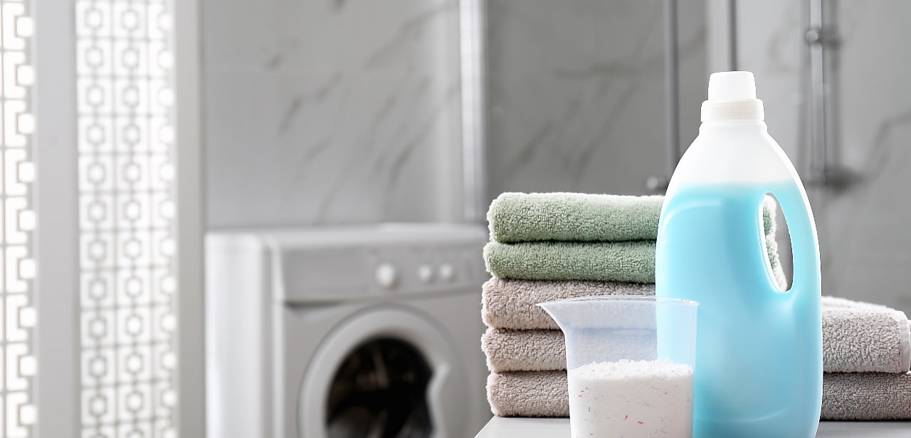 Towels and laundry detergent sitting on counter with washing machine in the background