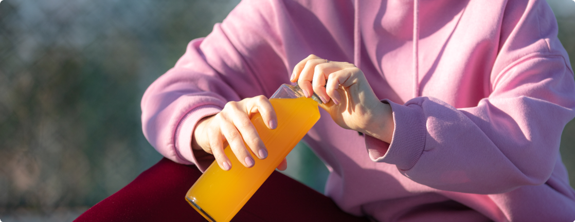 Person holding orange juice bottle