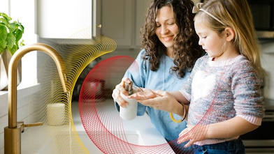 Mother and daughter wash their hands at kitchen sink