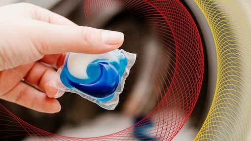 Hand placing a laundry detergent pod into a washing machine