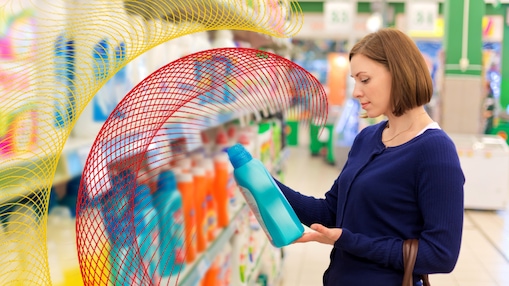 Woman examining a cleaning product bottle in a store aisle