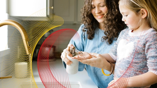 Adult helping a child use hand soap at a sink