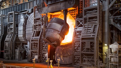Heavy goods vehicle driving on a road next to a forest and field