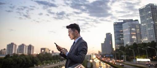 Side view of young businessman using smartphone outdoors