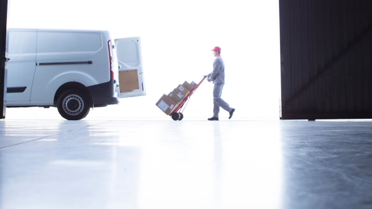 Man wheeling packages into the back of a van