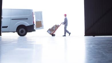 Man wheeling packages into the back of a van